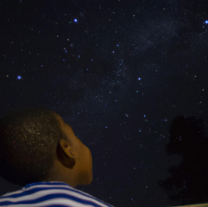 boy staring into dark sky with stars